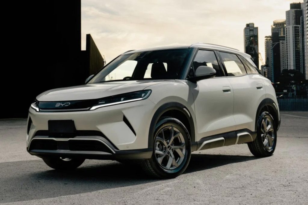 A sleek white BYD electric SUV parked with a modern city skyline in the background.